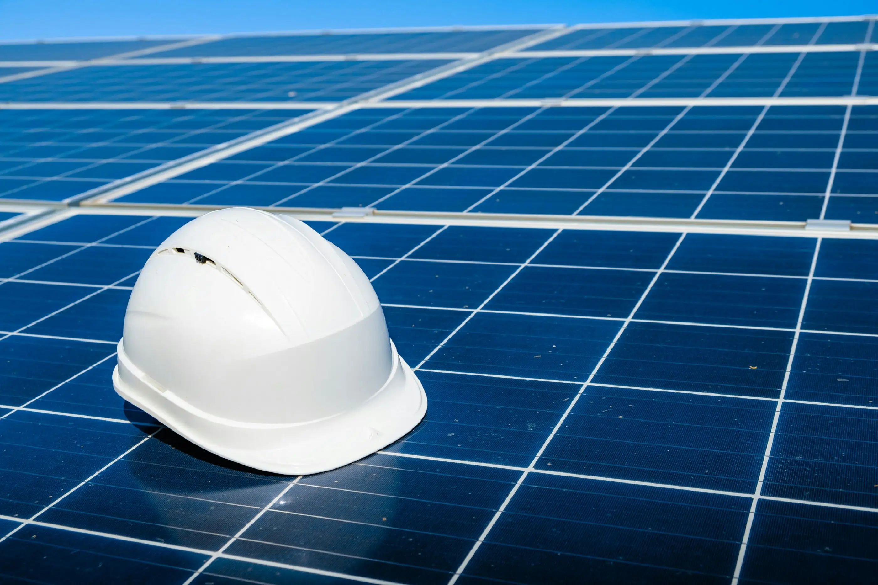 A hard hat resting on a solar panel, symbolising the importance of maintenance for efficient solar energy performance.